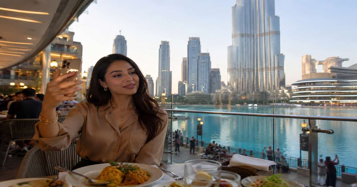 مؤثرة عربية في دبي تنشئ محتوى أمام أفق وسط مدينة دبي ضمن مشهد يعبر عن صناعة الترندات العربية