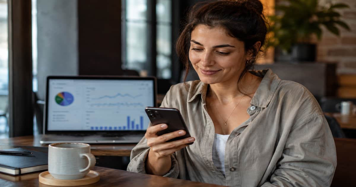 صانعة محتوى تراجع رسائل المتابعين والعملاء على هاتفها بينما تظهر إحصائيات الحساب في الخلفية، في مشهد يعبر عن قياس نجاح المحتوى بأكثر من عدد المشاهدات